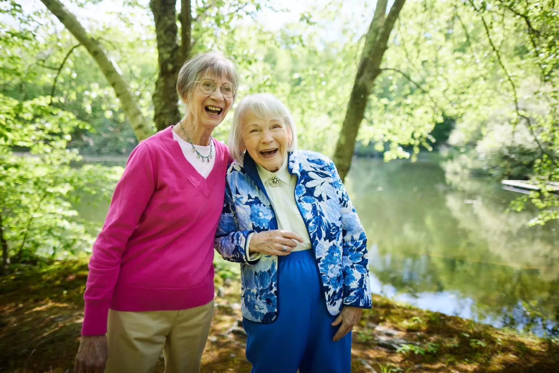 Two senior women laughing at lake