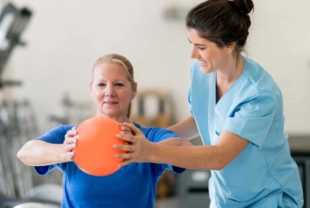 Caregiver and older woman doing physical therapy