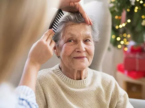 Caregiver combing senior woman's hair