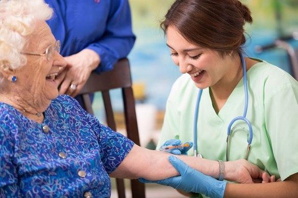 Nurse giving flu shot to senior woman