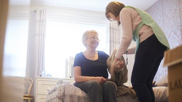 Caregiver helping senior put on sweater