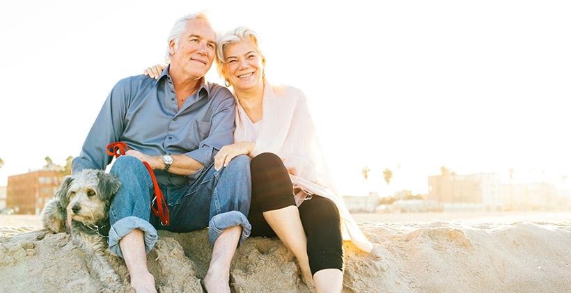 Older man and woman at beach with dog