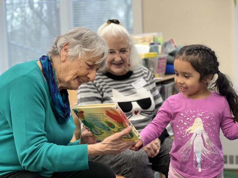Two seniors reading to a preschooler