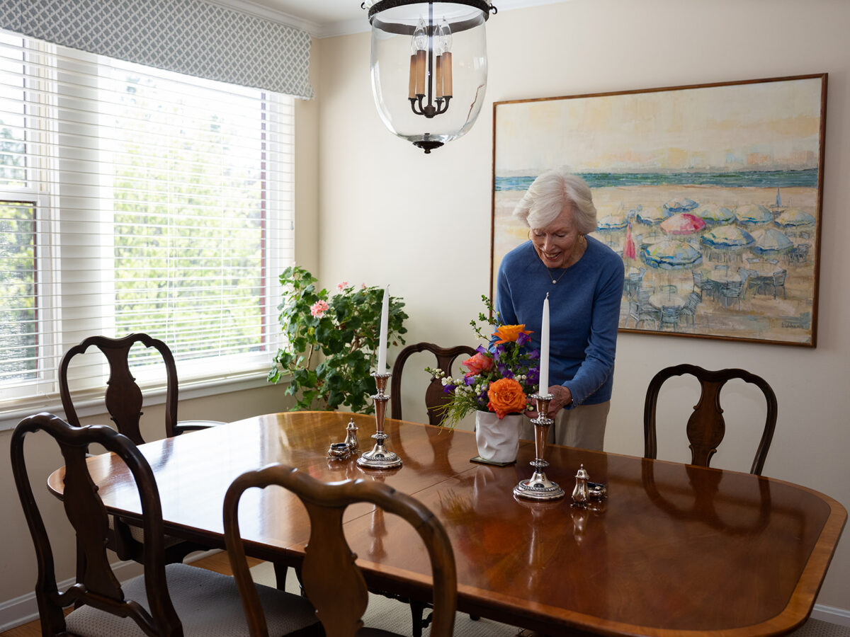 interior apartment dining room showing resident Jeanne arranging flowers