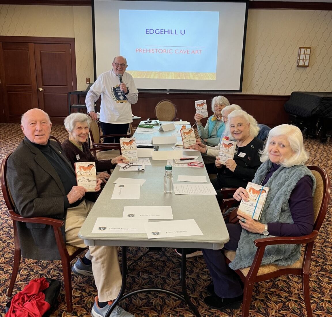 Ron Ebert presenting to a group of Edgehill residents during a class on prehistoric cave art, with a projected image illustrating early human expression.