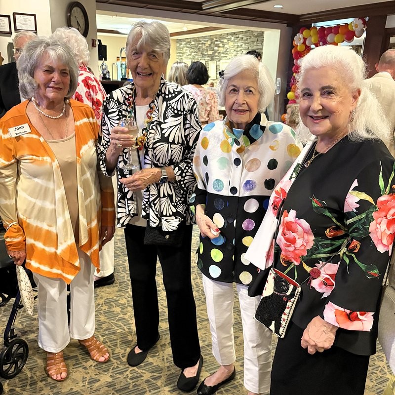 Residents Joan Weisman, Karen J., Esther B. and Nancy S. smile together during Edgehill's 27th anniversary celebration, dressed in colorful attire as they gather with friends at the festive cocktail party.